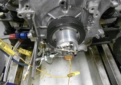 Schleifring am Wellenende, montiert in der Kurbelwellenriemenscheibe eines Motors auf dem Prüfstand, darunter Thermoelement-Stecker und Leitungen