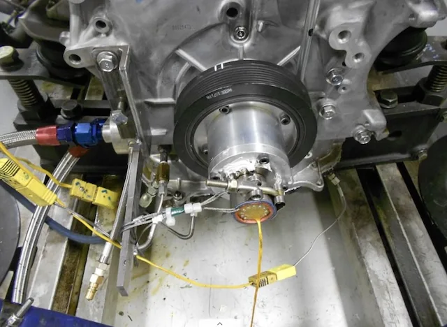 Front eines Motors auf dem Prüfstand, mit einem Schleifring in Wellenende-Bauweise am Kurbelwellenstirnende und Thermoelement-Steckverbindern