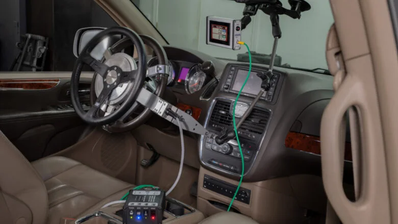 SW-SR2 steering wheel transducer installed in a minivan, with its cable running to the unit on the floor and an angle sensor held on the dashboard