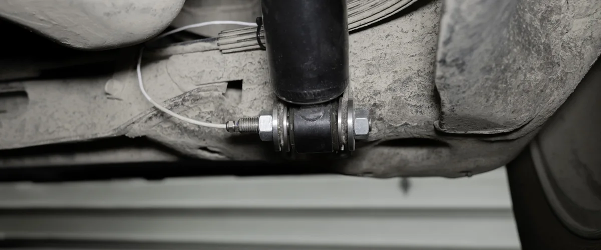 Shear pin transducer with its lead wire, in place of the bolt at the lower mount of a damper under a vehicle