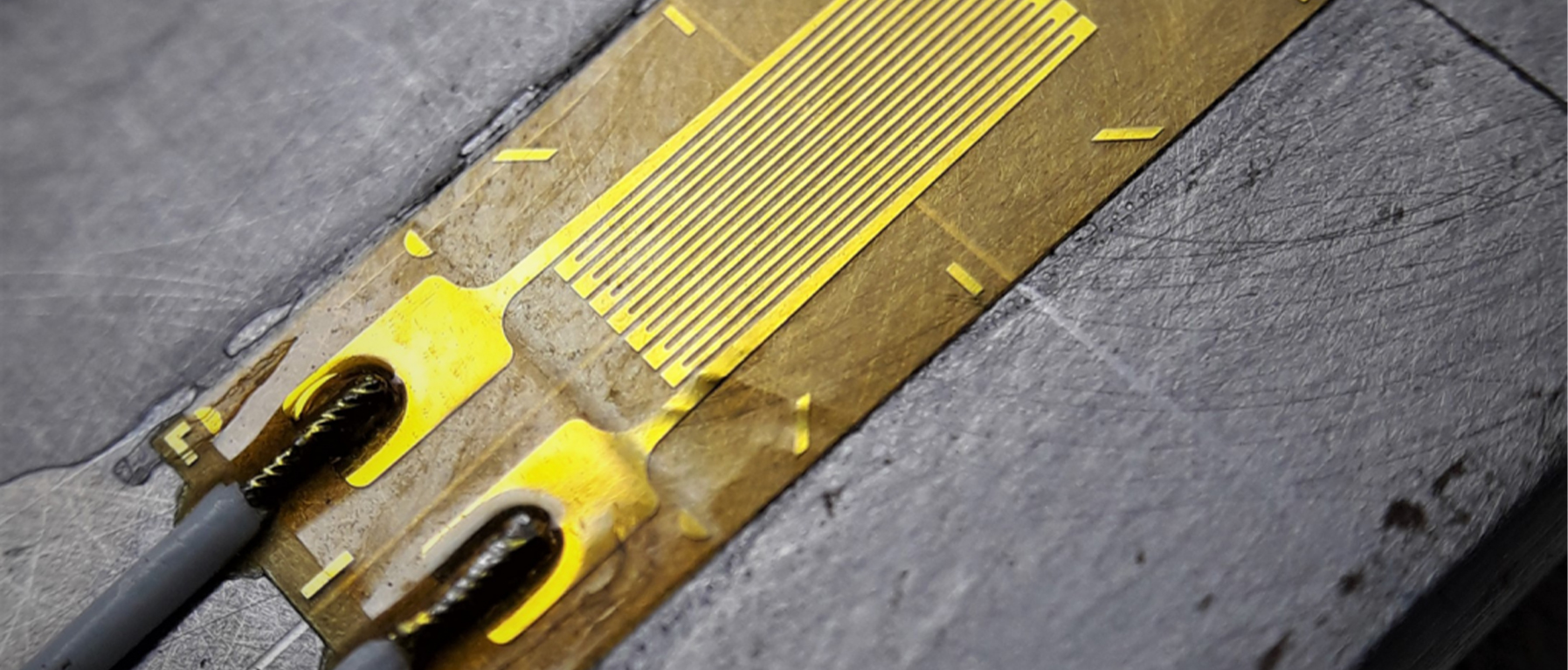 Strain gauge bonded to a metal part, with its lead wires